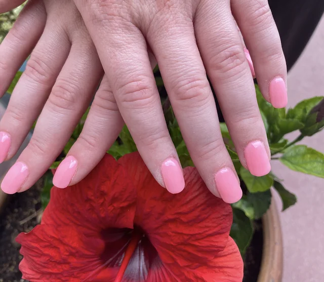 Spa manicure with soft pink polish and a red hibiscus flower
